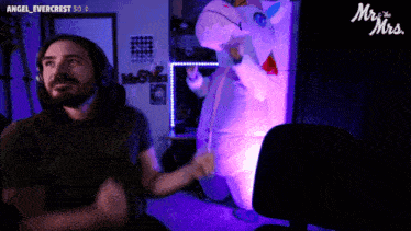 a man wearing headphones stands in front of a unicorn costume that says mr and mrs.