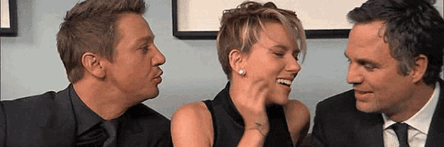 two men and a woman are laughing together in a room