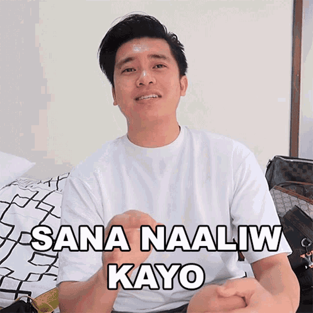 a man in a white shirt is sitting on a bed and says sana naaaliw kayo