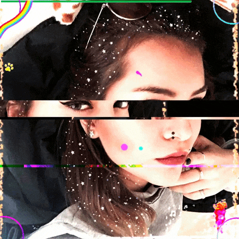 a girl with a nose ring looks at the camera with a rainbow behind her