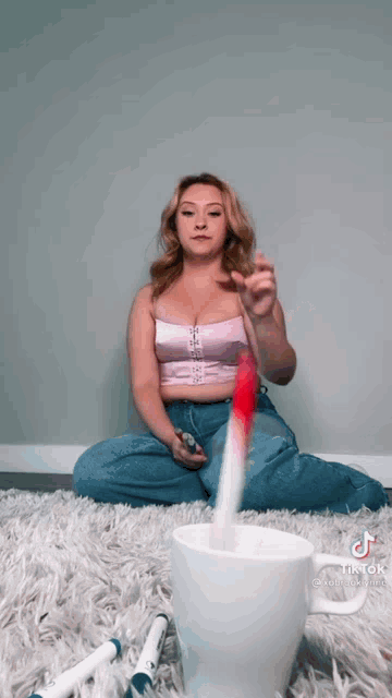 a woman is sitting on the floor next to a cup with markers on it .