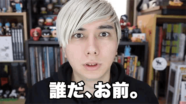 a man with white hair is standing in front of a bookshelf with chinese characters on it .