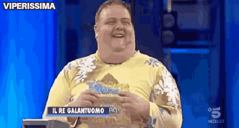 a man in a yellow shirt is laughing in front of a blue screen that says viperissima on it