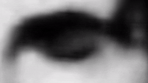 a black and white photo of a person 's eye with a blurry background .