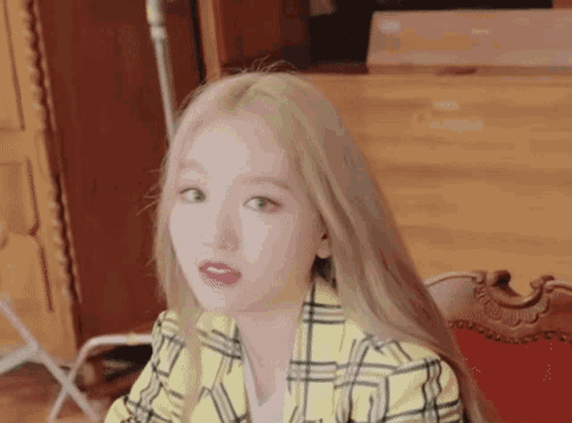 a woman with long blonde hair is wearing a yellow plaid jacket .
