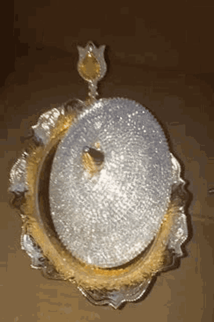 a silver plate with rhinestones on it is sitting on a wooden table .