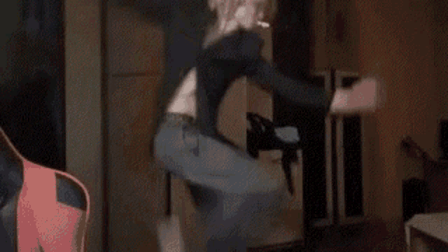 a woman is jumping in the air while smoking a cigarette in a living room .