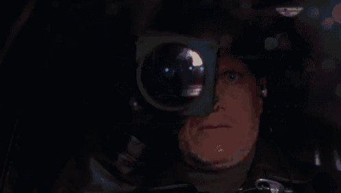 a man is looking through a telescope in the dark .