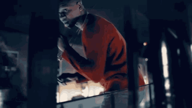 a man in a red shirt is standing on a balcony with his hands outstretched