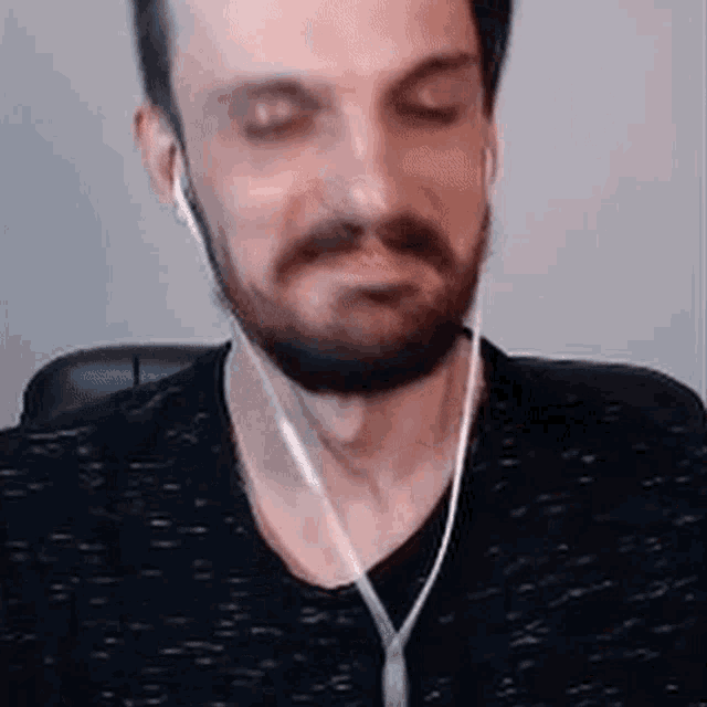 a man with a beard is wearing headphones and looking at the camera .