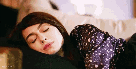 a woman is sleeping on a couch with her eyes closed .