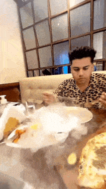 a man is sitting at a table eating food with smoke coming out of the plate