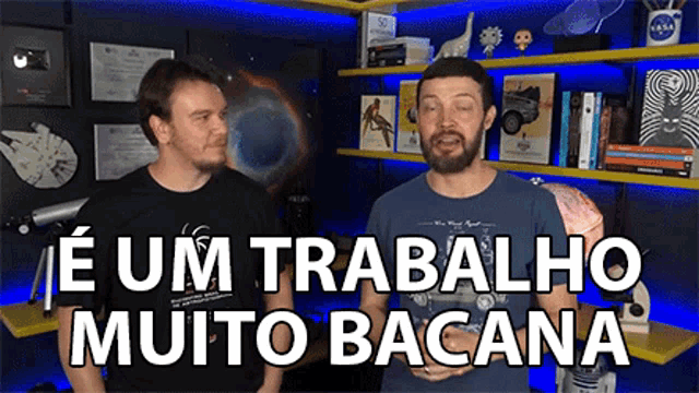 two men are standing next to each other in front of a bookshelf and the words e um trabalho muito bacana are on the screen .