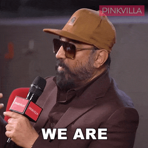 a man wearing a hat and sunglasses is holding a microphone and saying we are