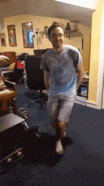 a man wearing a tie dye shirt is dancing in a room