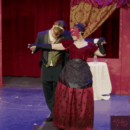 a man in a tuxedo and a woman in a red dress are dancing