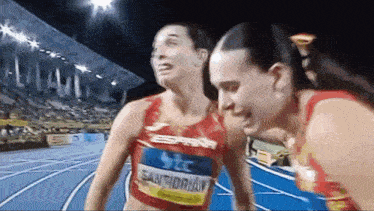 two female runners on a track with one wearing the name santidrian on her shirt