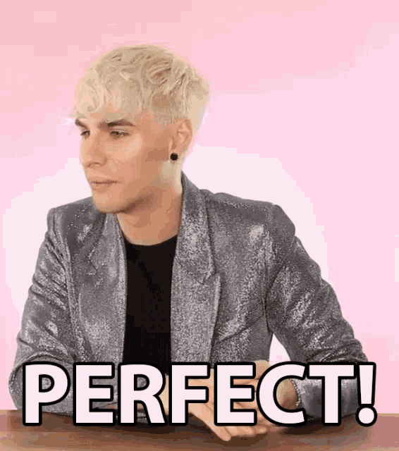 a man in a silver jacket is sitting at a table with the words `` perfect '' written on the screen .