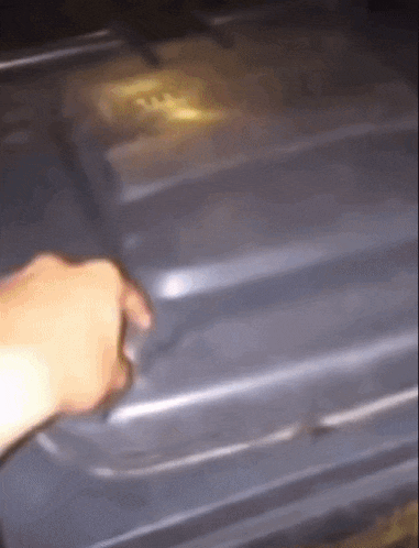 a person 's hand is reaching into a trash can with a yellow sticker on it that says ' recycle '