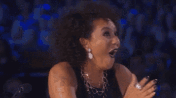 a woman with a surprised look on her face is holding her hands up in the air .
