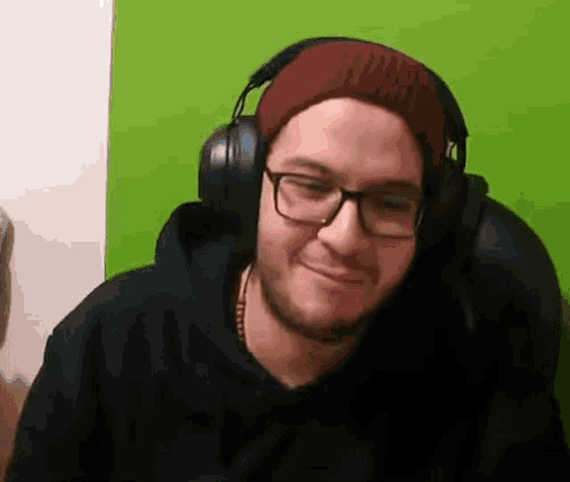 a man wearing glasses and headphones is smiling .