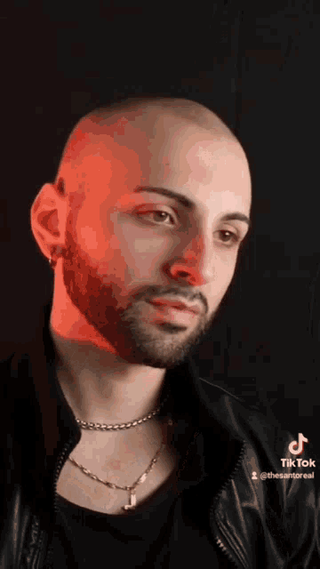 a bald man with a beard is wearing a black jacket