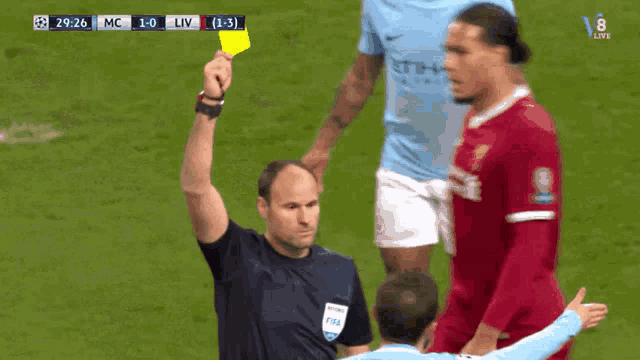 a referee holds up a yellow card during a soccer game between mc and liv