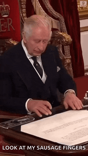 a man in a suit and tie is sitting at a desk with a piece of paper in front of him .
