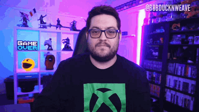 a man wearing glasses stands in front of a shelf with a game over sign on it
