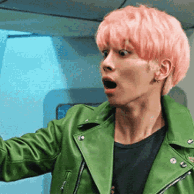 a man with pink hair is wearing a green jacket .
