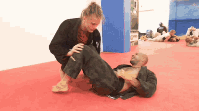 a man is laying on the ground with a woman kneeling on his back