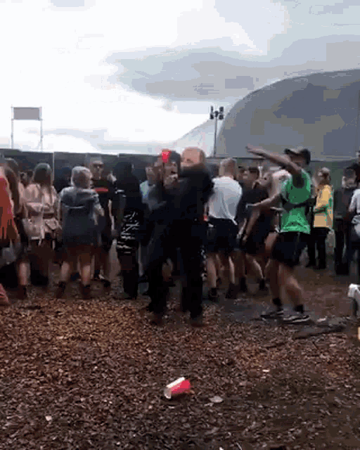 a group of people are dancing in the dirt at a music festival .
