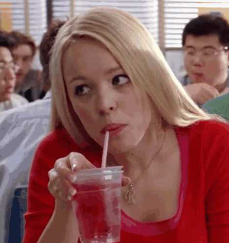 a woman is drinking from a plastic cup with a straw in her mouth .