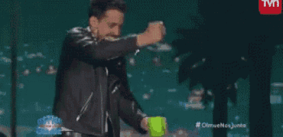 a man in a leather jacket is dancing on a stage in front of a tv screen .