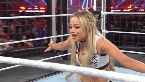 a woman in a wrestling ring with a w logo on the back of her shirt