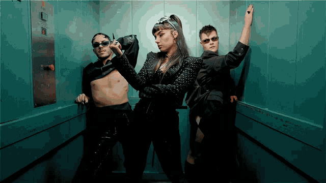 two men and a woman are in an elevator and the woman is wearing a crown