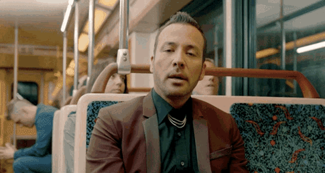 a man in a suit is sitting on a bus with his eyes closed