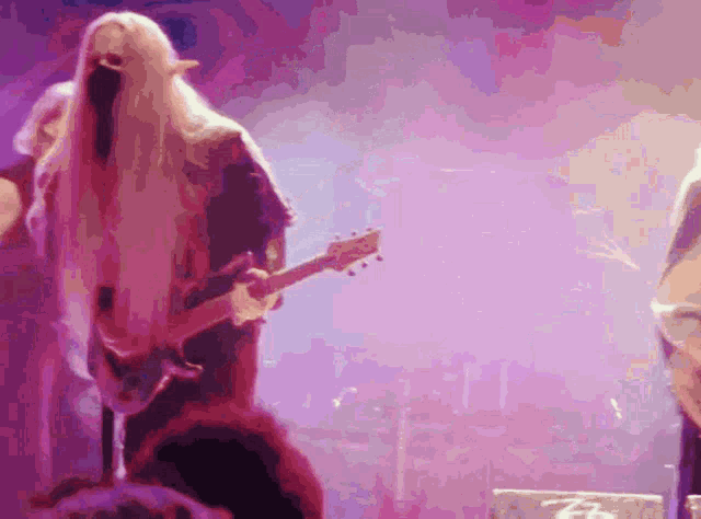 a woman with long blonde hair playing a guitar on stage