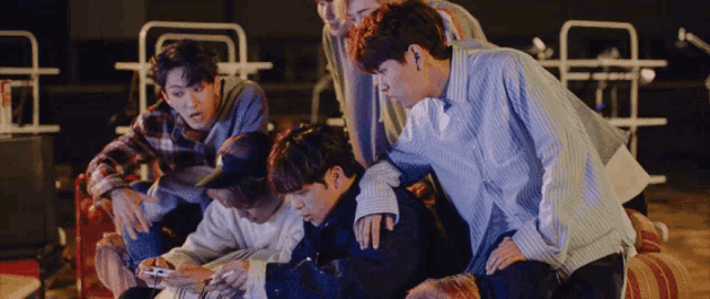 a group of young men are looking at a cell phone together