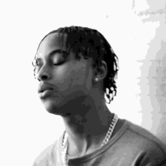 a black and white photo of a man wearing a chain around his neck