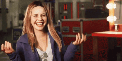 a woman in a purple jacket is laughing with her hands outstretched .