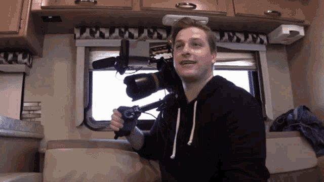a man in a black hoodie is holding a camera in front of him