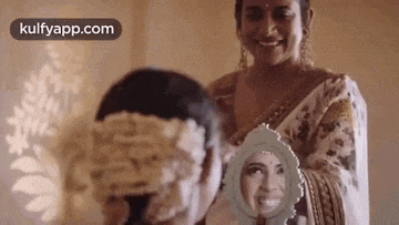 a woman is looking at herself in a mirror while smiling .