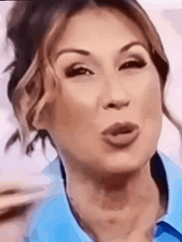 a woman wearing a blue shirt is blowing a kiss .