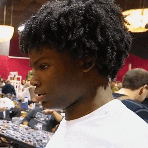 a man with curly hair is wearing a white shirt that says ' a ' on the back