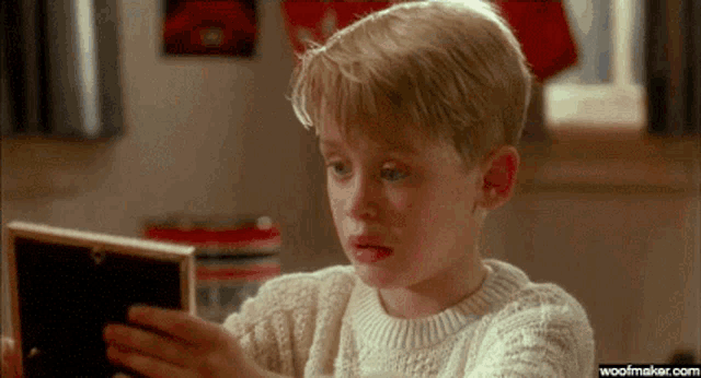a young boy is looking at a picture in a frame .