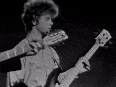 a black and white photo of a man playing a bass guitar with a yamaha logo on the headstock
