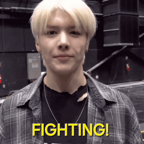 a young man in a plaid shirt says fighting in yellow letters