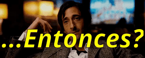 a man in a tuxedo is sitting in front of a sign that says entonces