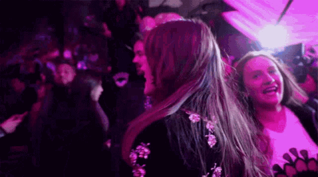 a woman with long hair is dancing in a crowd of people at a party .